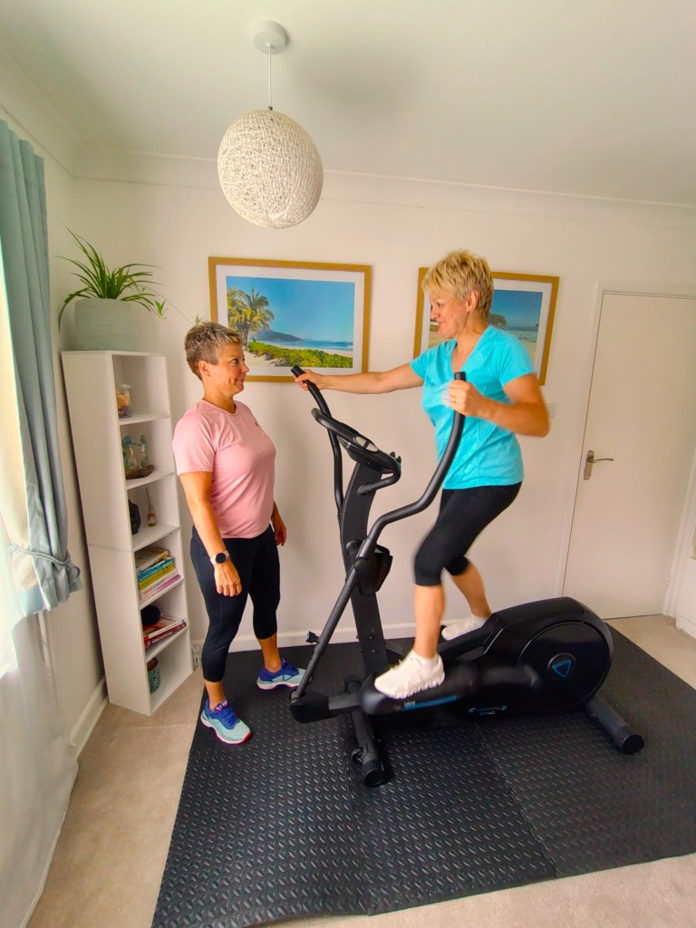 Personal Trainer with client on cross-trainer